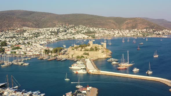 aerial drone of Bodrum Castle as a boat enters the marina in Mugla Turkey on a sunny summer afternoo