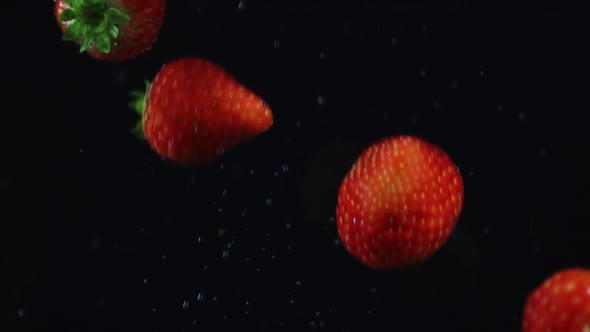 Strawberries fall in water black background Slowmotion