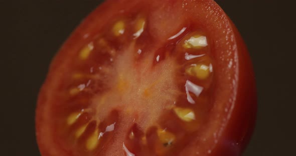 Rotate of the Halves of Fresh Ripe Cut Tomato on a Dark Background