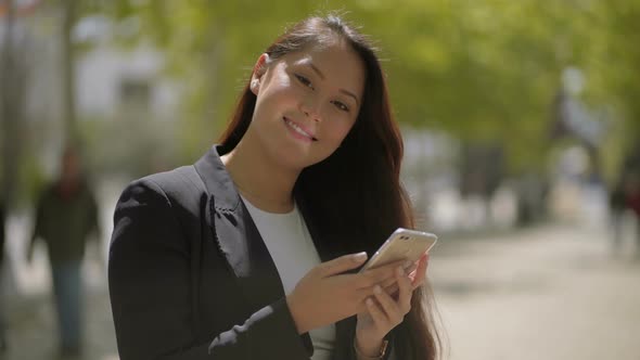 Girl Using Smartphone and Smiling at Camera