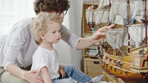 Curious Toddler Boy Looking at Ship Model alt