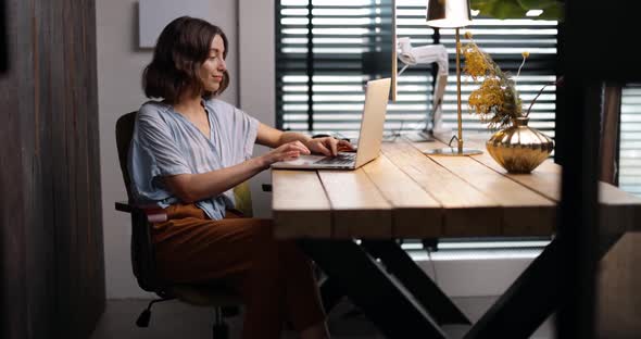 Woman Works on a Laptop at Cozy Home Office