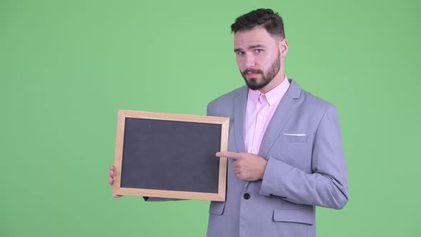 Happy Young Bearded Businessman Holding Blackboard and Giving Thumbs Up