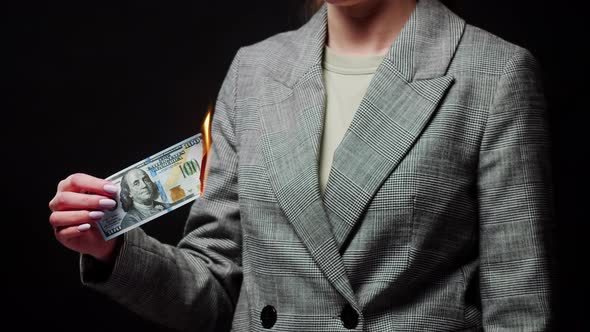 Woman Holding Burning American Hundred Dollar Banknote on Black Background