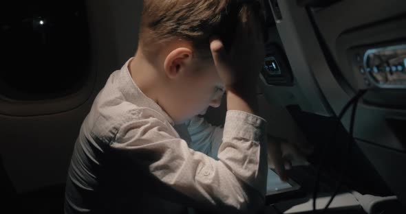 Boy Traveling By Plane and Playing Chess Game on Digital Tablet