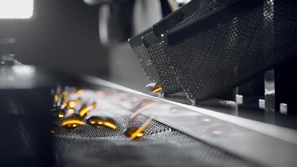 Yellow Gel Capsules Move on the Conveyor Belt of the Medical Machine