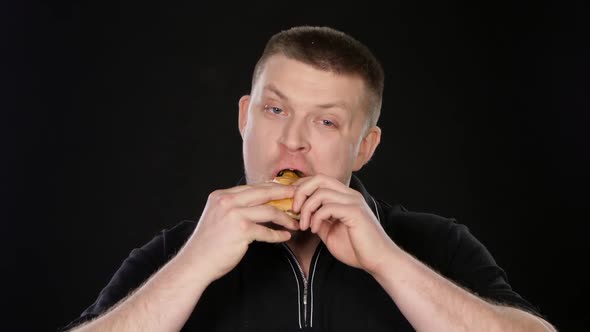 Man Looks Into the Camera and Then Starts To Eat a Hamburger