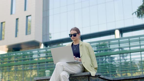 Closeup Portrait of a Young Woman Sitting on the Stairs Outside the Business Center Typing on Her