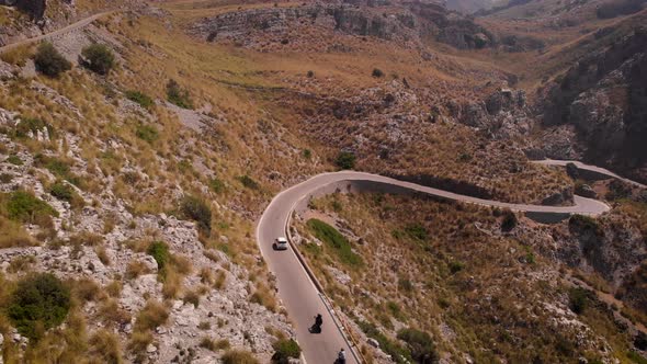 AERIAL: Following car and motorbike on serpentine road in mountains of Mallorca