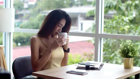 Young pretty woman writing in appointment book at coffee shop