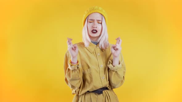 Cute Young Girl Praying Over Yellow Background. Woman Begging Someone. .