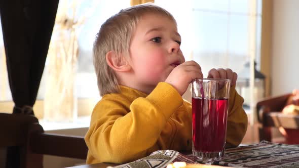 Child Boy with Blonde Hair Baby Drinking Lemonade in Cafe