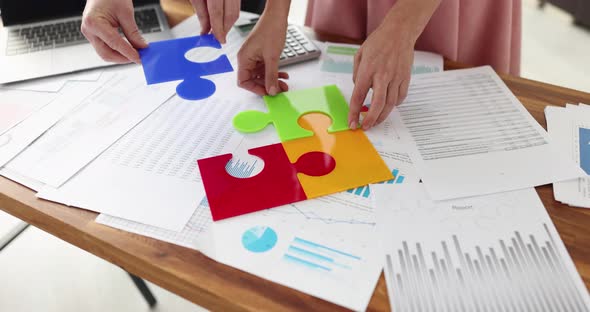 Business People Folding Colorful Puzzle at Table with Documents Closeup  Movie Slow Motion