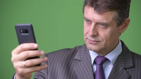 Mature Handsome Businessman Against Green Background