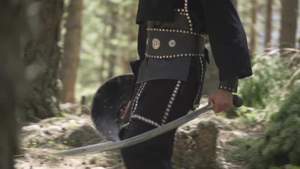 Soldier walking in the forest with sword and shield in hand. alt