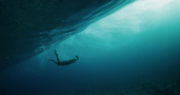 Man swimming beneath breaking ocean wave