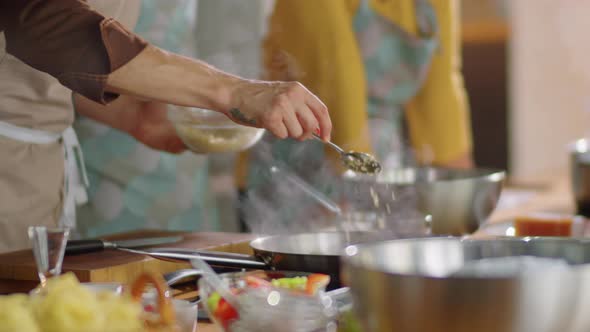 Chef Adding Cheese to Frying Pan while Giving Cooking Master Class