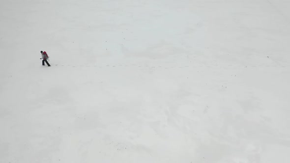 Human with Heavy Backpack Walking By Snow Desert in Alaska. View From Top.