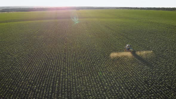 Aerial View of Farming Tractor Spraying on Field with Sprayer, Herbicides and Pesticides at Sunset