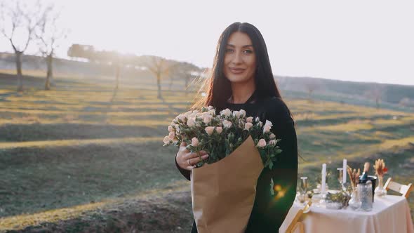 The Portrait of a Charismatic Young Woman in Nature Holding a Bouquet of Beautiful Flowers in Her