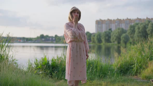 Wide Shot Portrait of Confident Coquette Transgender Woman Standing on Green Meadow at Lake Sending