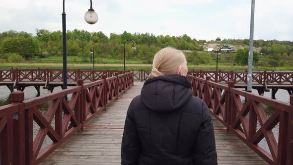 Blonde Girl Walking on the Bridge and Looks Into the Camera.