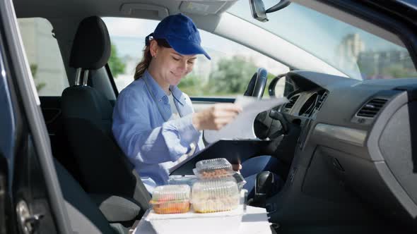 Young Girl Driver Works As Courier in Food Delivery Service From a Supermarket or Restaurant Sits in