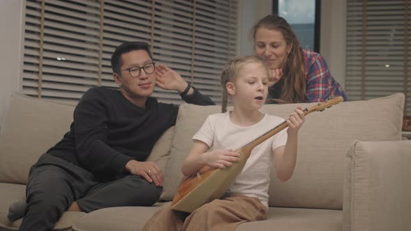 Girl playing the balalaika on the couch at living room