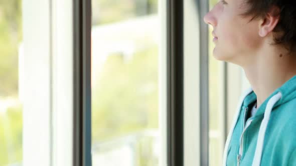 Thoughtful schoolboy looking through window