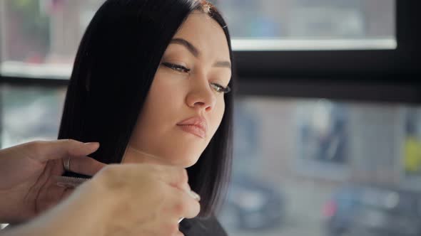 Hairdresser Cutting Hair of a Beautiful Serious Brunette Woman