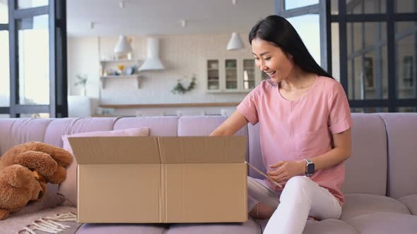 An Attractive Young Asian Woman Unpacking a Parcel Box