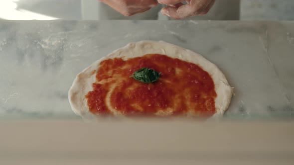 Chef in the Restaurant Prepares a Pizza and Decorates It with Tomato Mozzarella and Basil