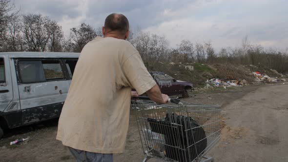 Back View of Male Pushing Shopping Cart at Landfill