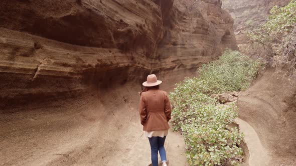 Woman walking inside in ravine with big stones"