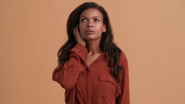 A puzzled brunette african american woman shrugging shoulders