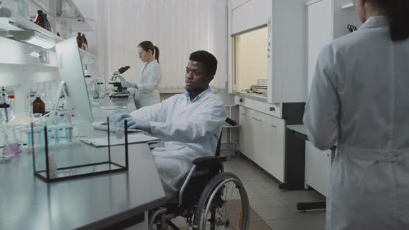 Male Scientist in Wheelchair Working in Lab and Posing alt