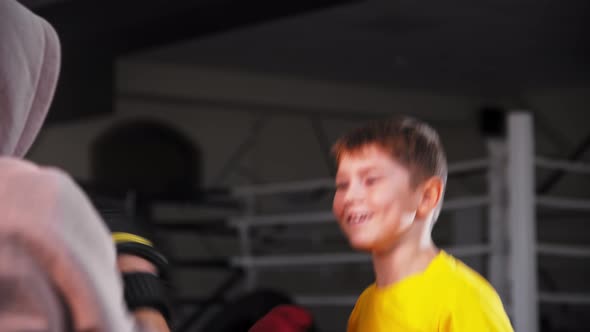 Little Smiling Boy Doing Boxing Hitting the Pads on the Hands of His Coach and Dodges a