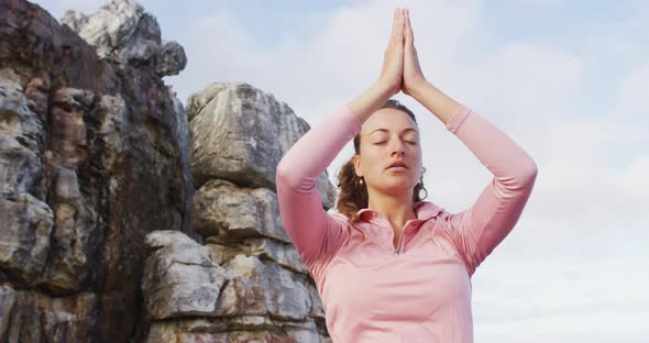 Caucasian woman practicing yoga meditation outdoors in rural mountainside setting