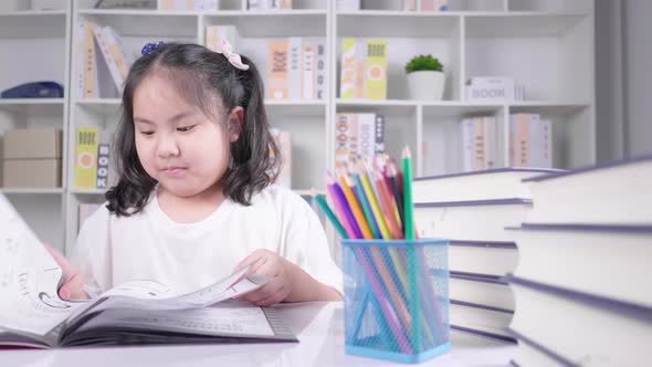 Beautiful inteligent young girl sat at home table reading  open book