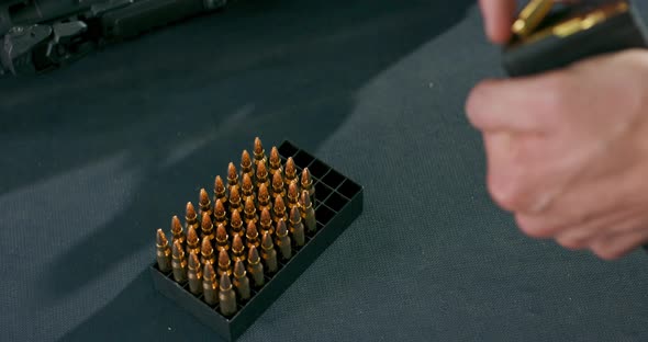 Closeup of Male Hands Loading Bullets Into a Gun Magazine Clip at a Firing Range