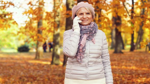 Senior Woman Calling on Smartphone at Autumn Park