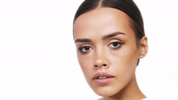 A Beautiful Brunette Turns To the Camera Closeup on a White Background