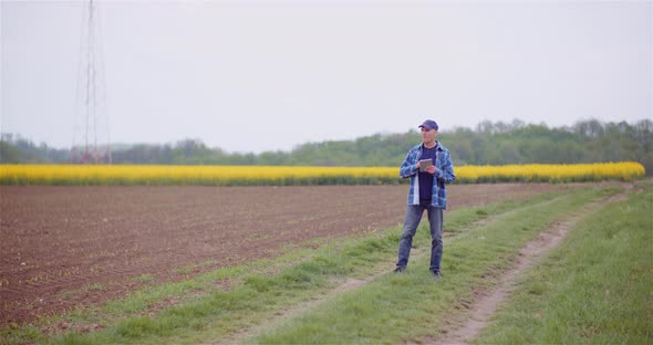 Farmer Examining Agricultural Field While Working on Digital Tablet Computer at Farm