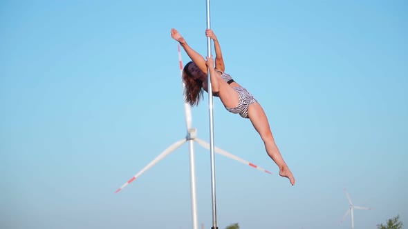 Beautiful girl athlete performs a trick on the pole. Aerial gymnastics. Cool split. Pole dance.