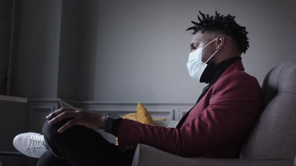 Black Business Man Works Behind a Laptop in a Protective Mask