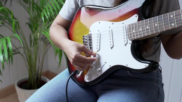 Young woman playing electric guitar at home