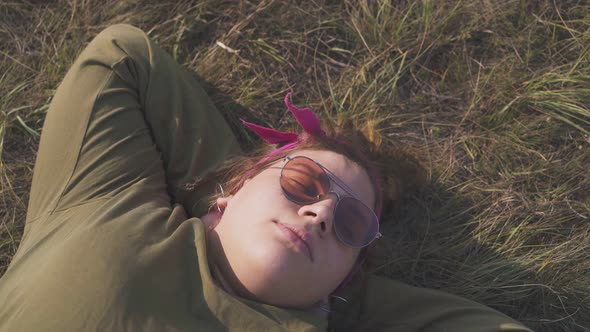 Plump Young Lady in Sunglasses Sleeps on Dry Grass