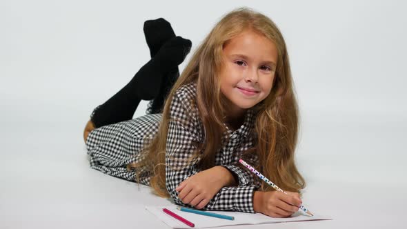 Studio shot girl on the floor drawing with pencils