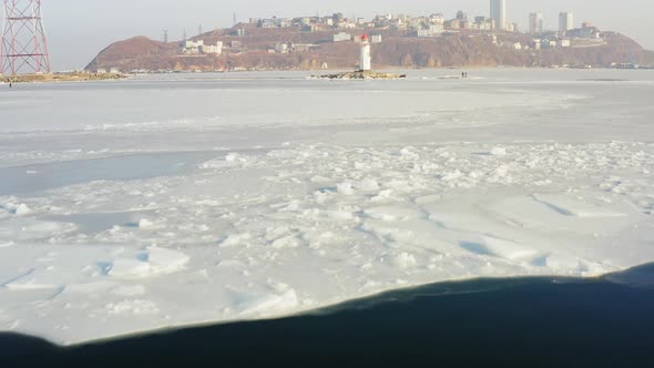 Flight Over the Frozen Sea and Drone View of Tokarevsky Lighthouse at Dawn