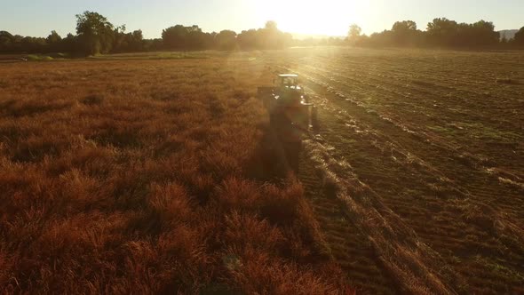 Aerial shot of combine in field at sunrise